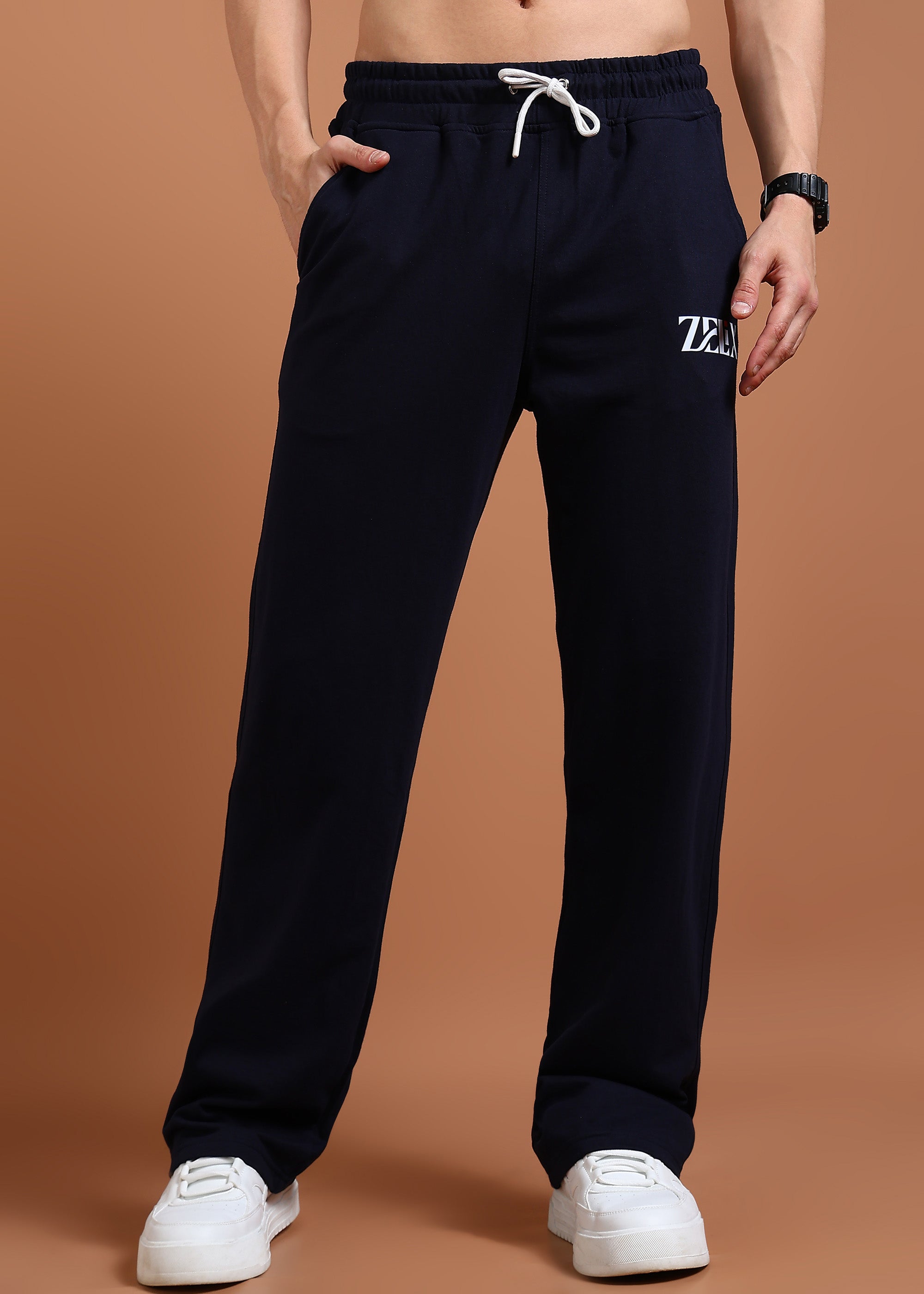 A person wearing navy blue comfort fit joggers with an elasticated waistband and drawstring, paired with a white top and white sneakers.