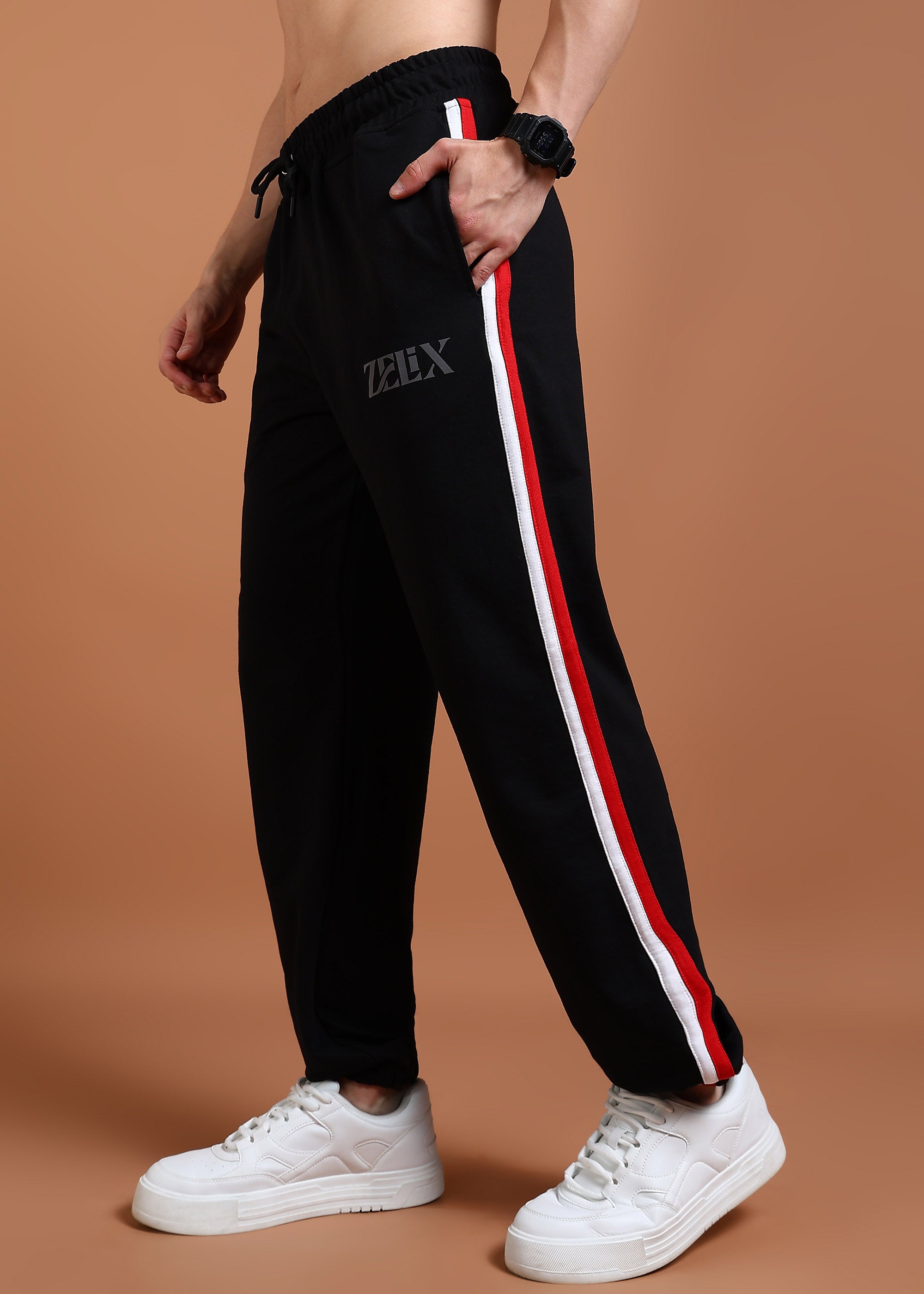 A person wearing black joggers with a red and white stripe on the side, and a drawstring at the waist. The brand 'Zelix' is visible on the joggers.