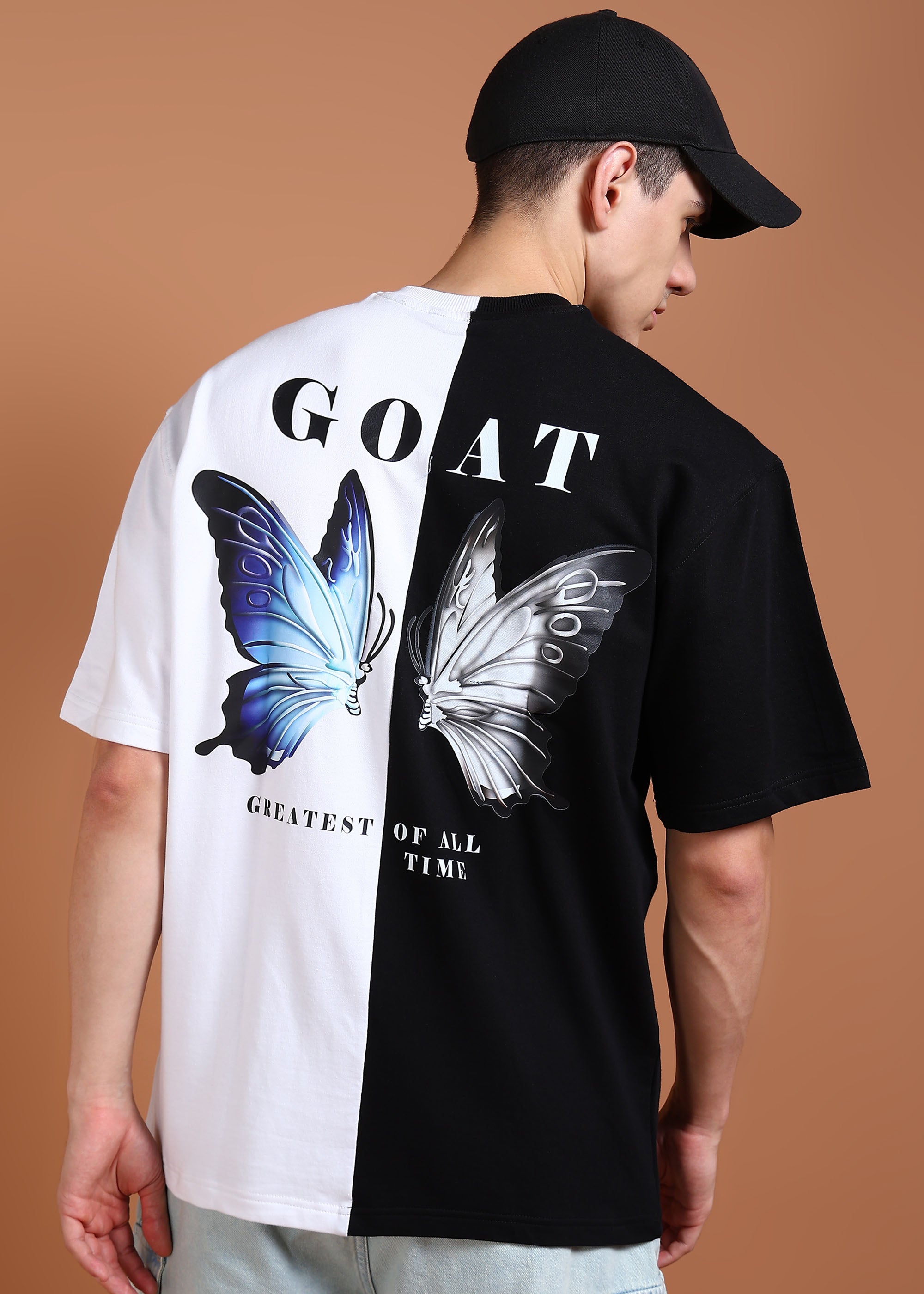 A person wearing an oversized black and white t-shirt with a graphic of a butterfly and the text 'GOAT' on the back.
