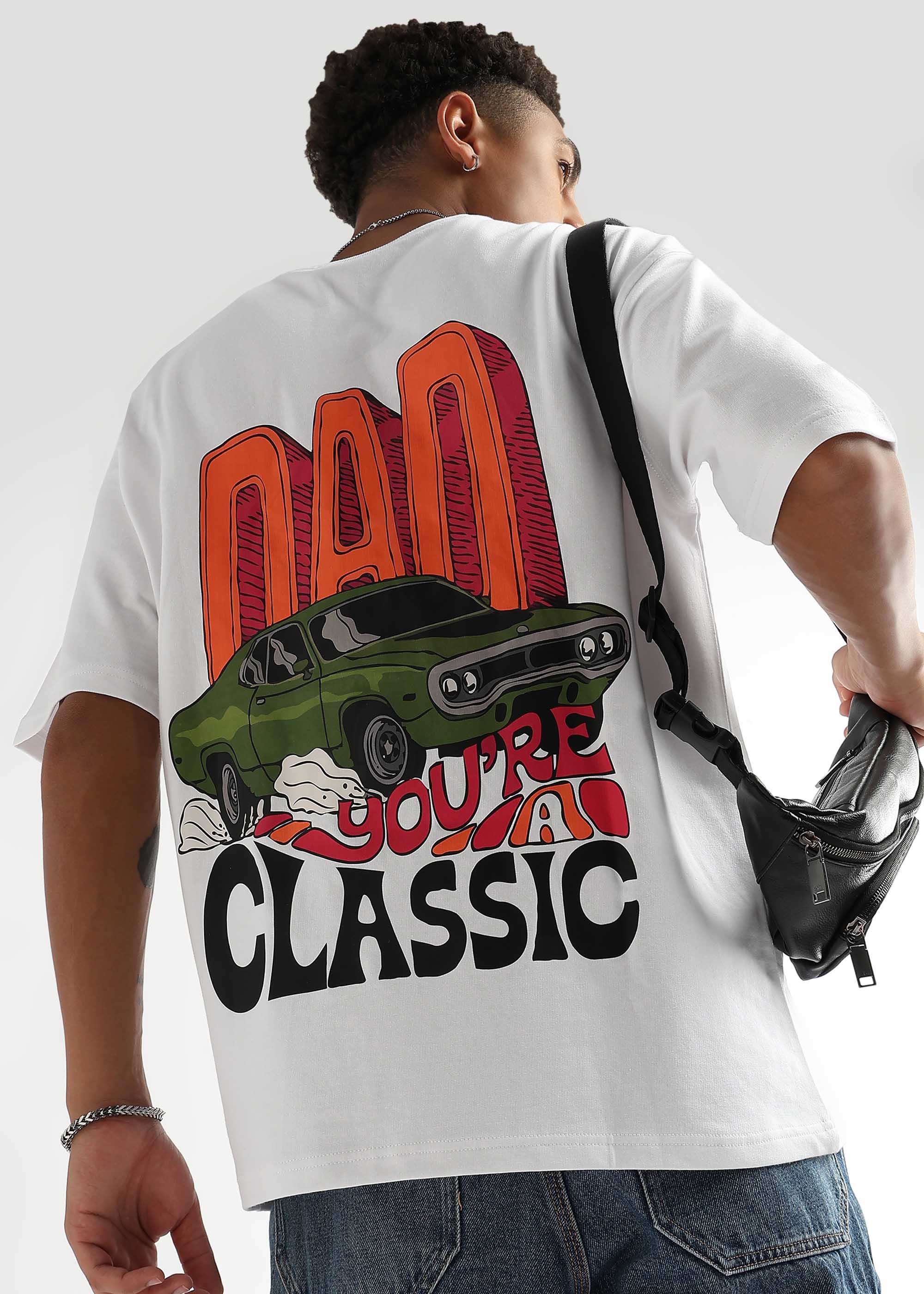 A person wearing an oversized white t-shirt with a retro-inspired graphic that includes the text 'DAD CLASSIC' and an image of a car.