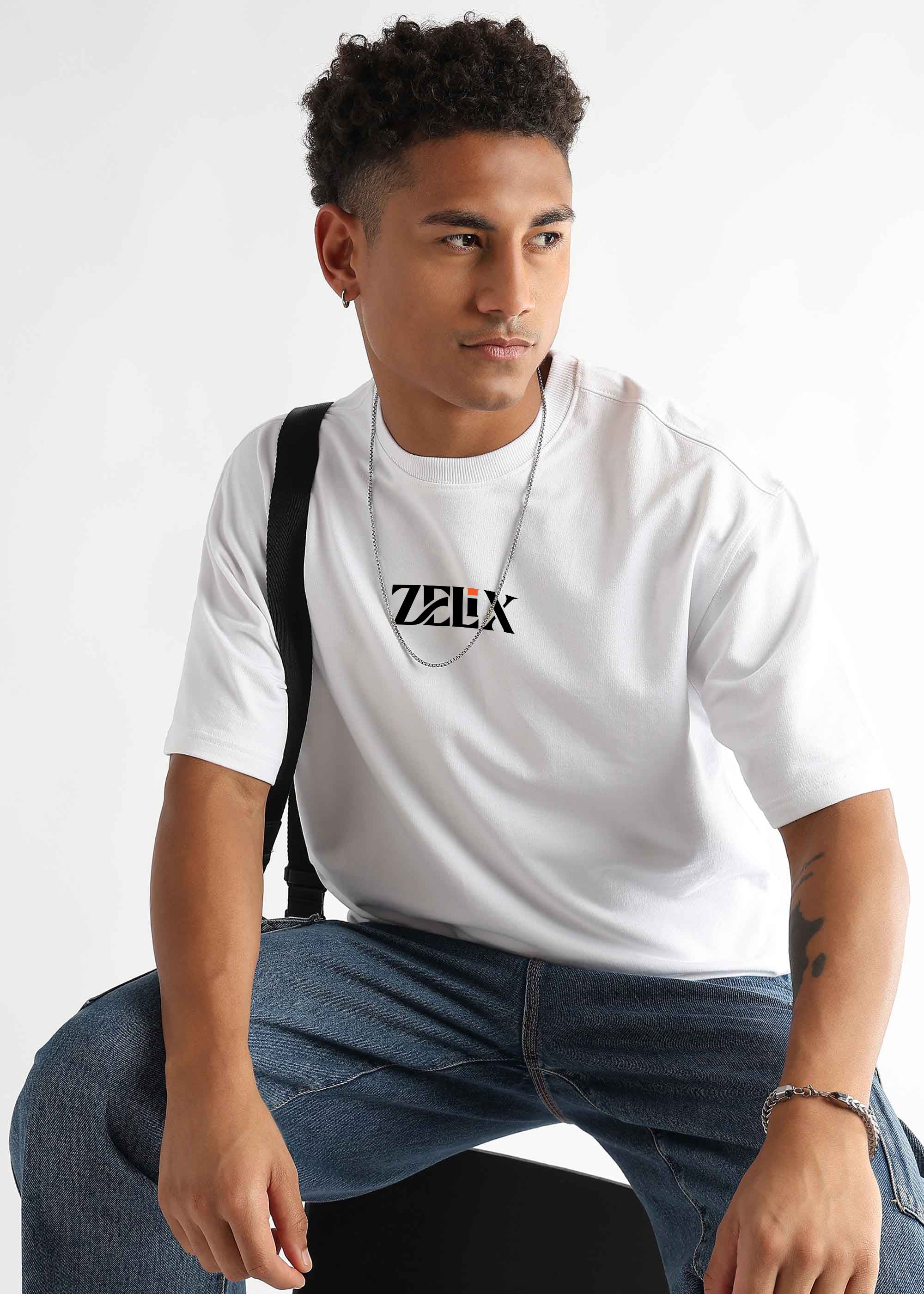 Man wearing a white t-shirt with a logo, sitting against a plain background