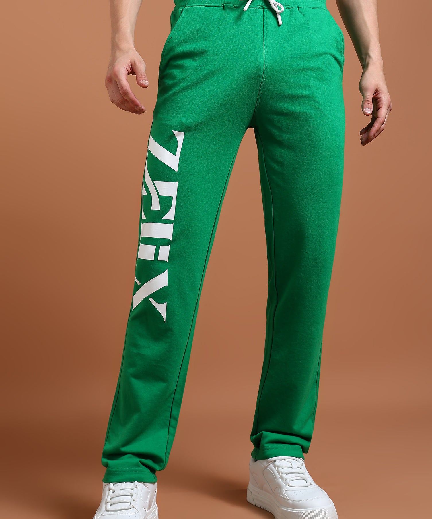 A model wearing green unisex baggy fit joggers with a drawstring waistband and white sneakers.