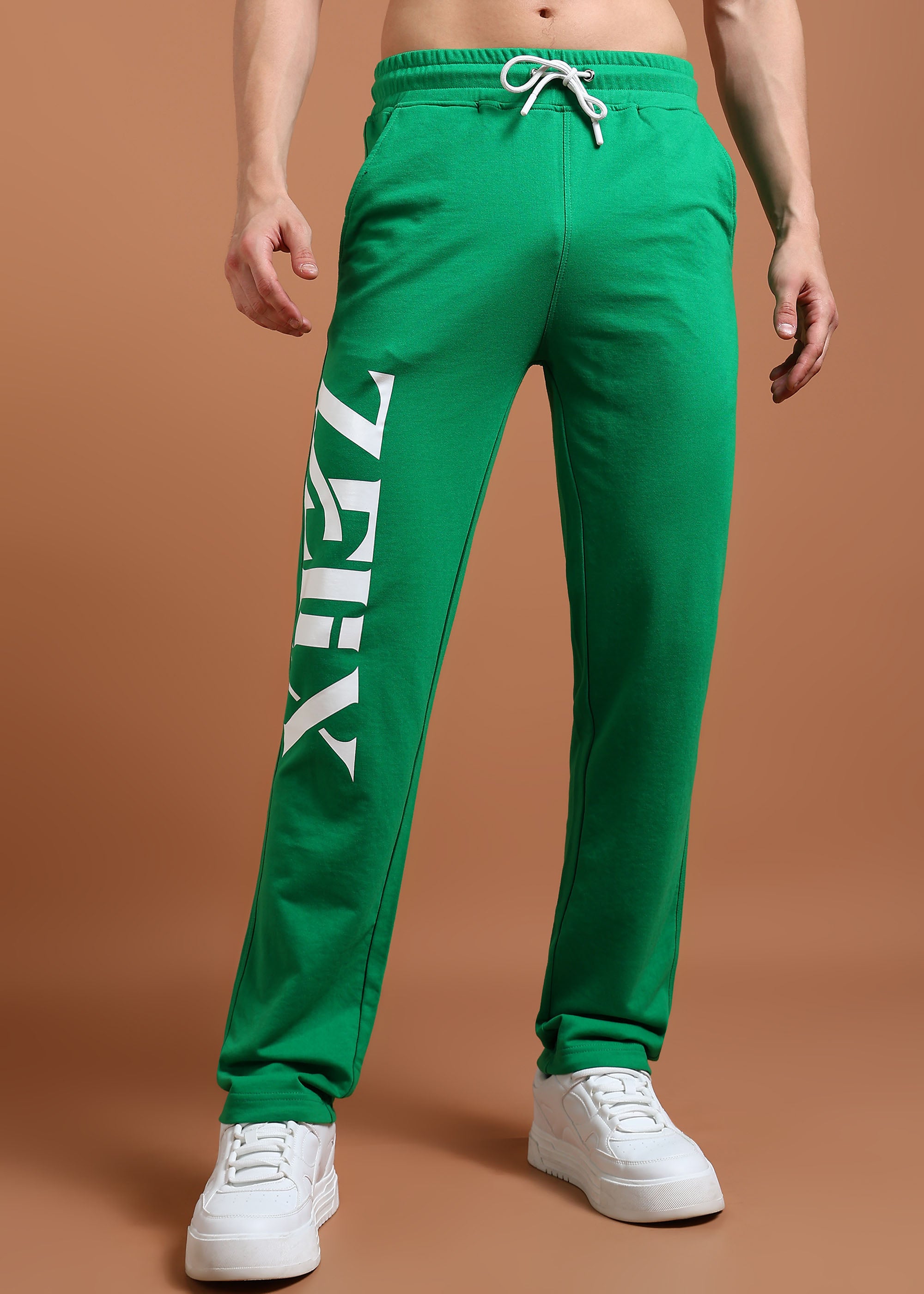 A model wearing green unisex baggy fit joggers with a drawstring waistband and white sneakers.