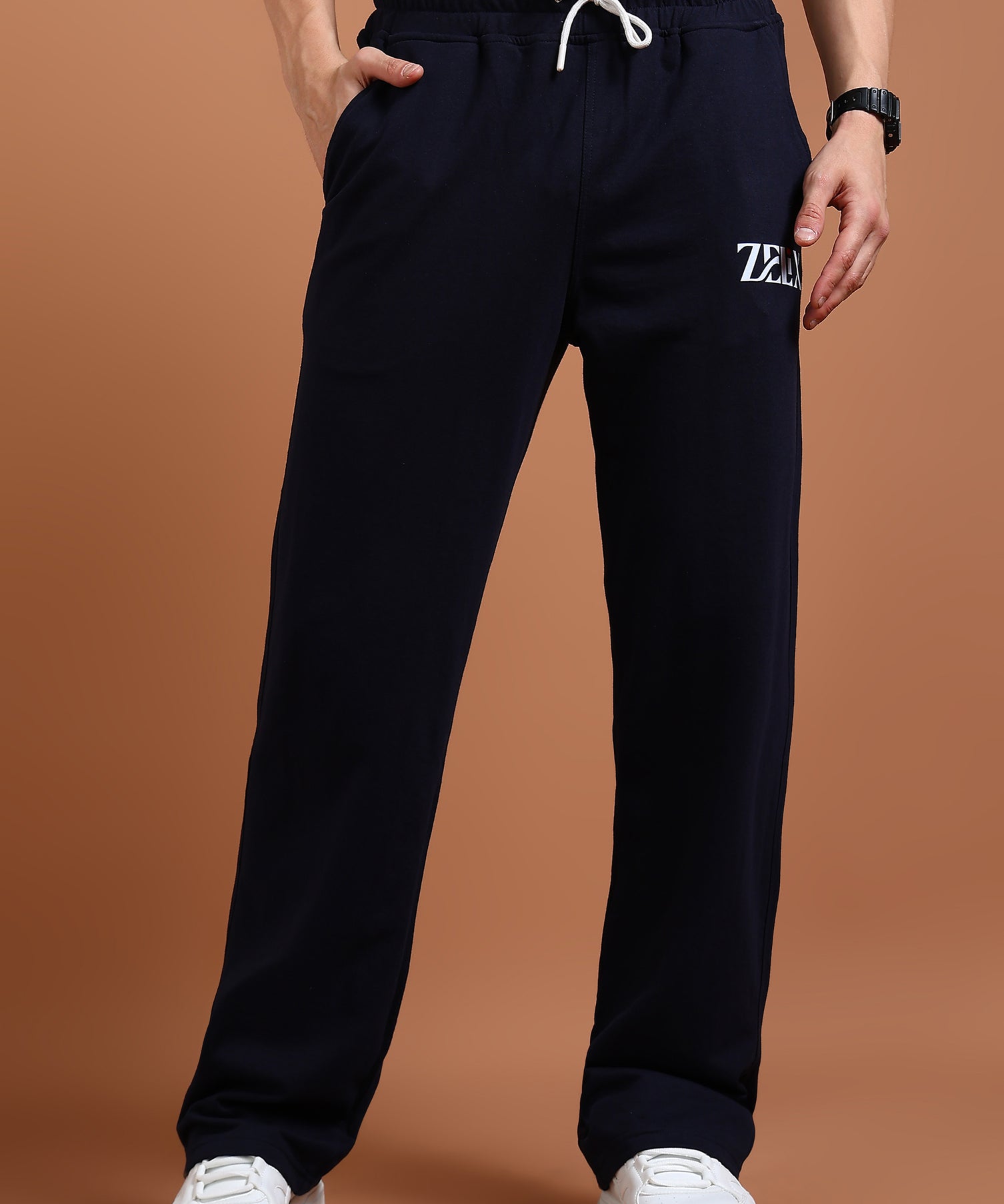A person wearing navy blue comfort fit joggers with an elasticated waistband and drawstring, paired with a white top and white sneakers.
