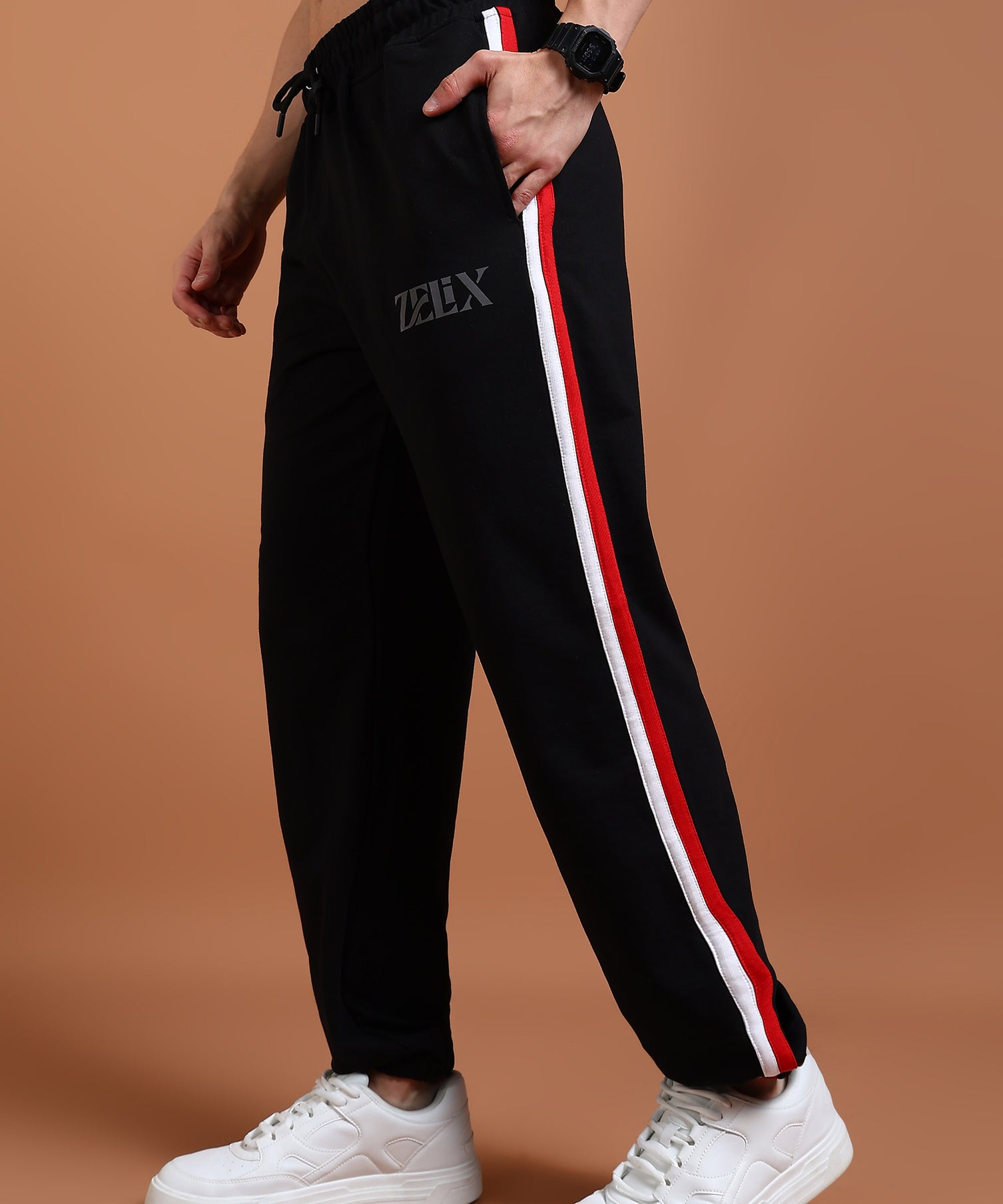 A person wearing black joggers with a red and white stripe on the side, and a drawstring at the waist. The brand 'Zelix' is visible on the joggers.