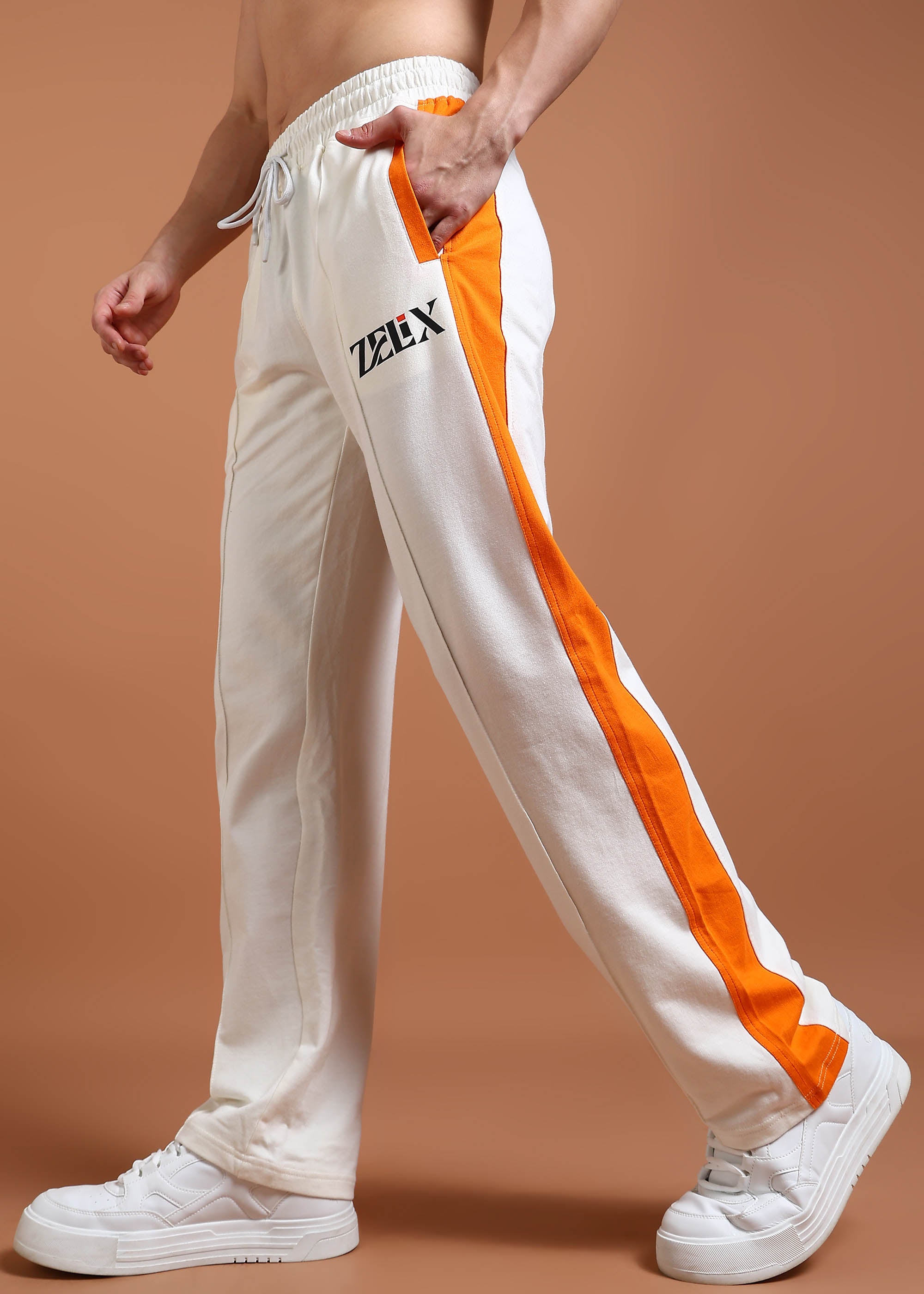 A pair of joggers with off-white and orange color contrast, featuring a drawstring waistband and a brand logo on the left leg.