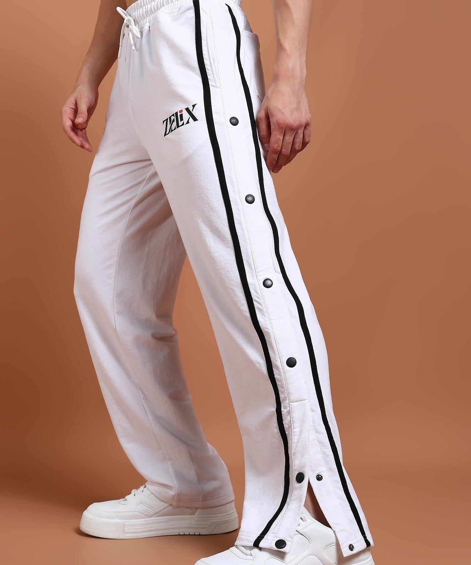 A person wearing white joggers with black contrast panels and a drawstring waist.