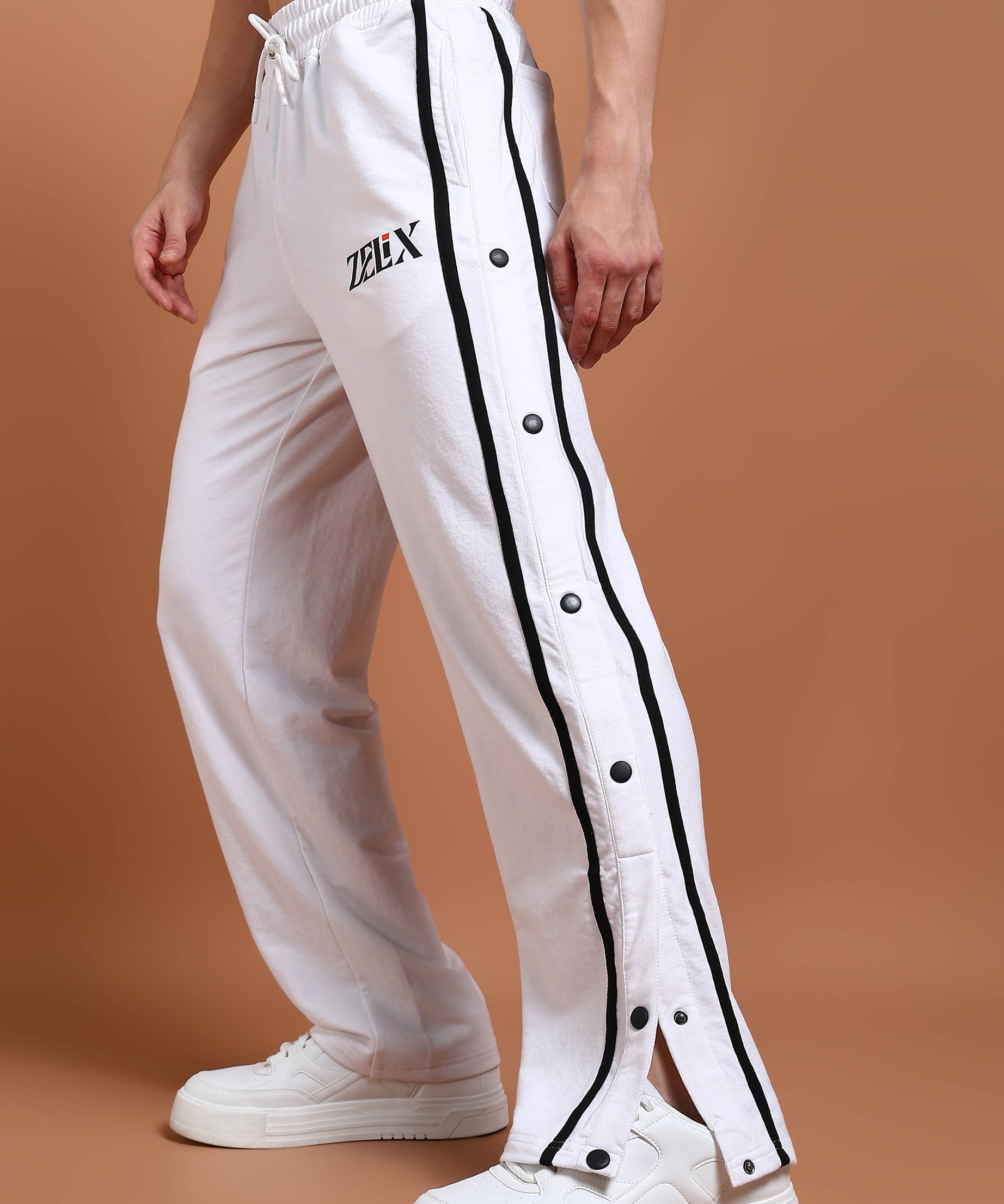 A person wearing white joggers with black contrast panels and a drawstring waist.