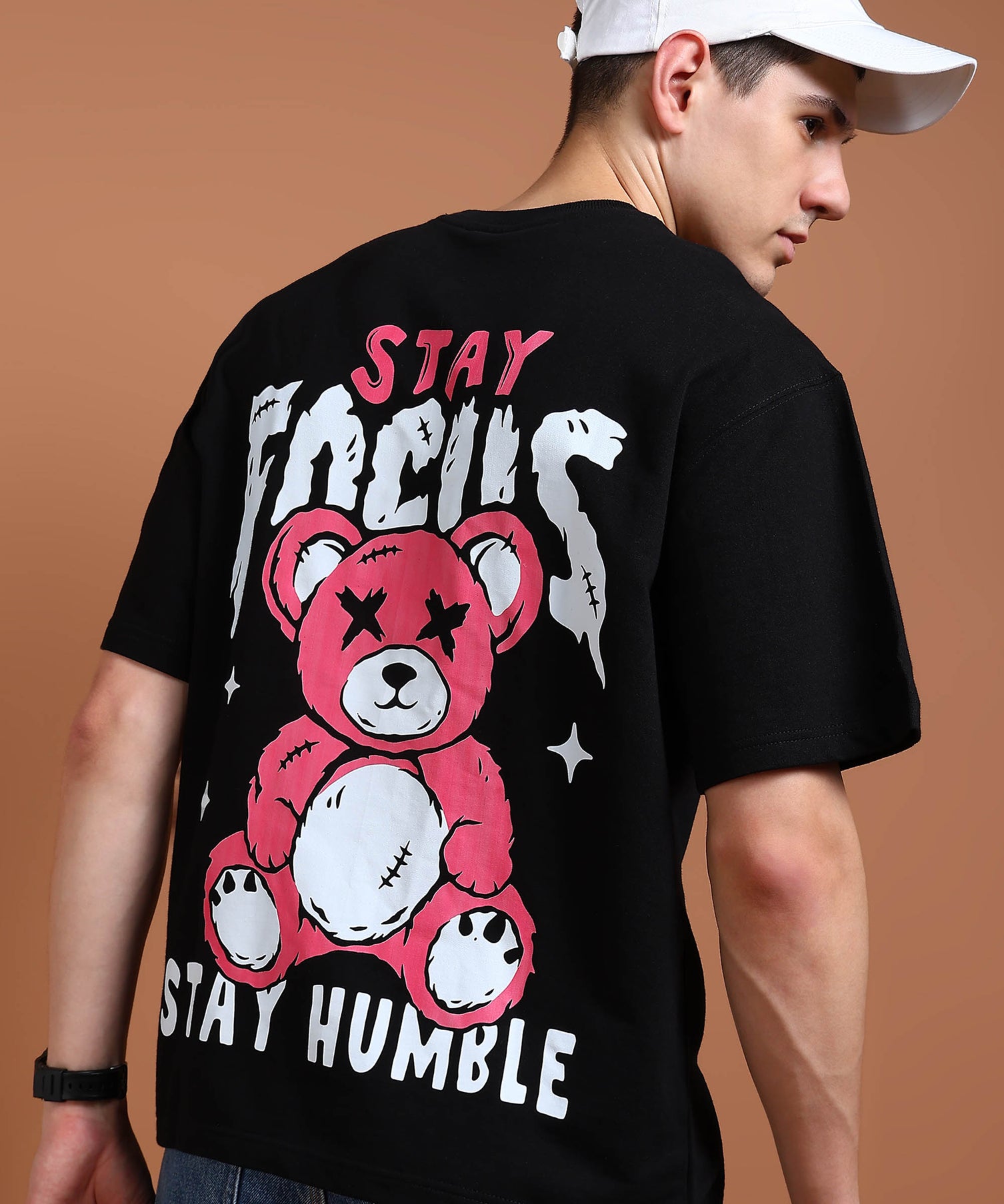 A person wearing a black oversized t-shirt with a graphic that includes a teddy bear and text saying 'STAY FOCUS STAY HUMBLE'.