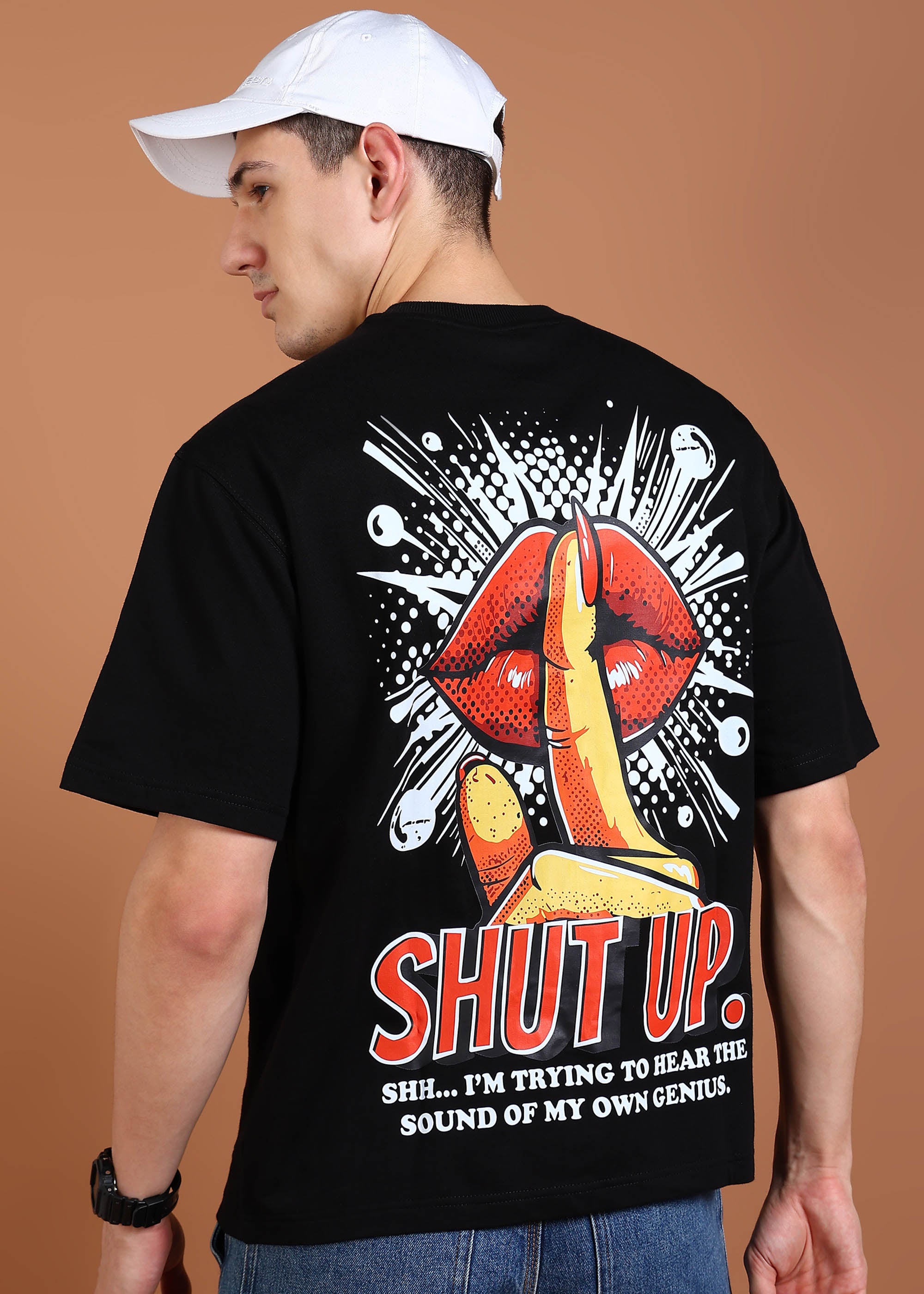 A person wearing a black oversized t-shirt with a graphic print on the back showcasing red lips and the text 'SHUT UP. I'm trying to hear the sound of my own sense.