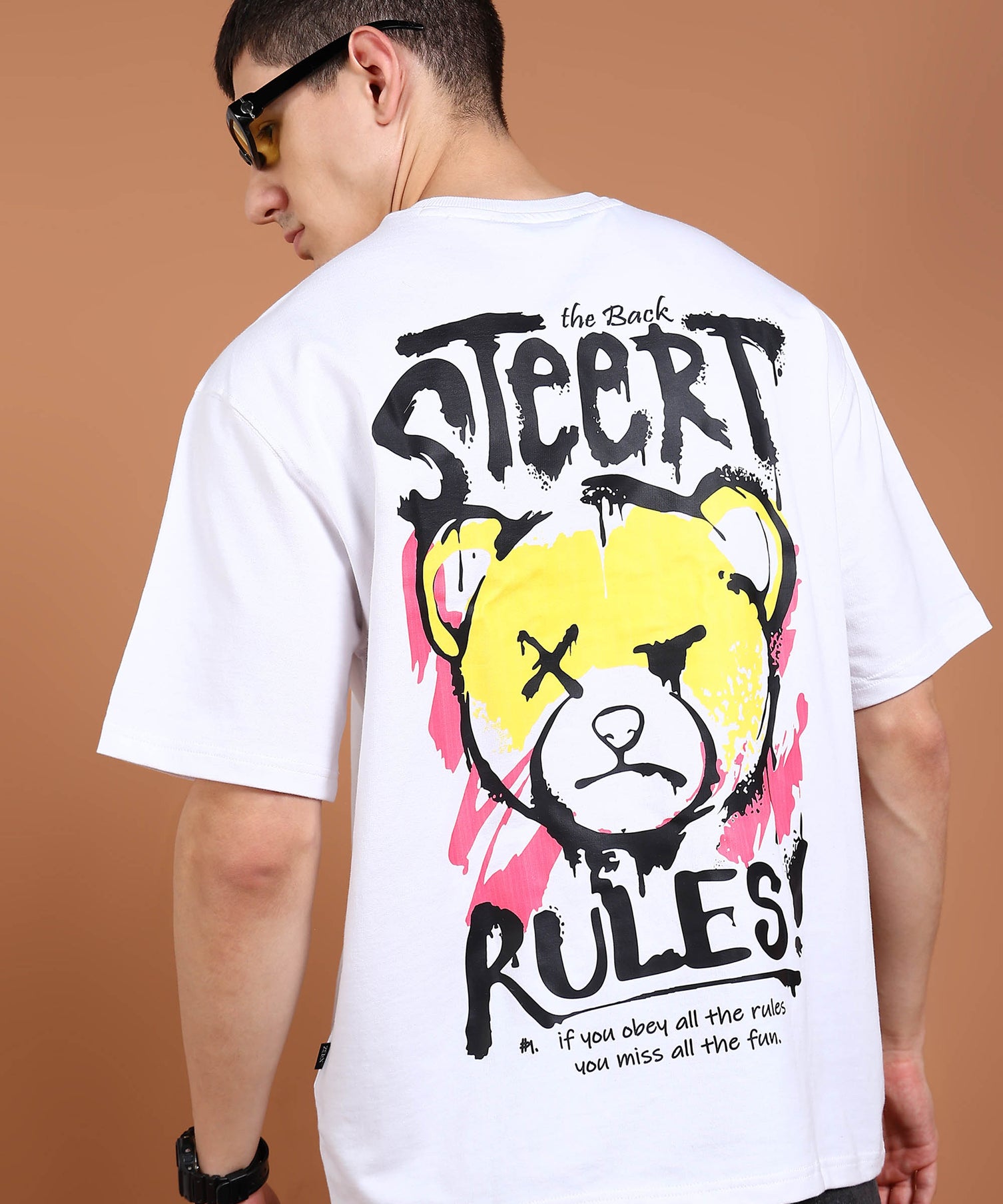 A person wearing an oversized white t-shirt with a graphic of a bear and the text 'STREET RULES' on the back.