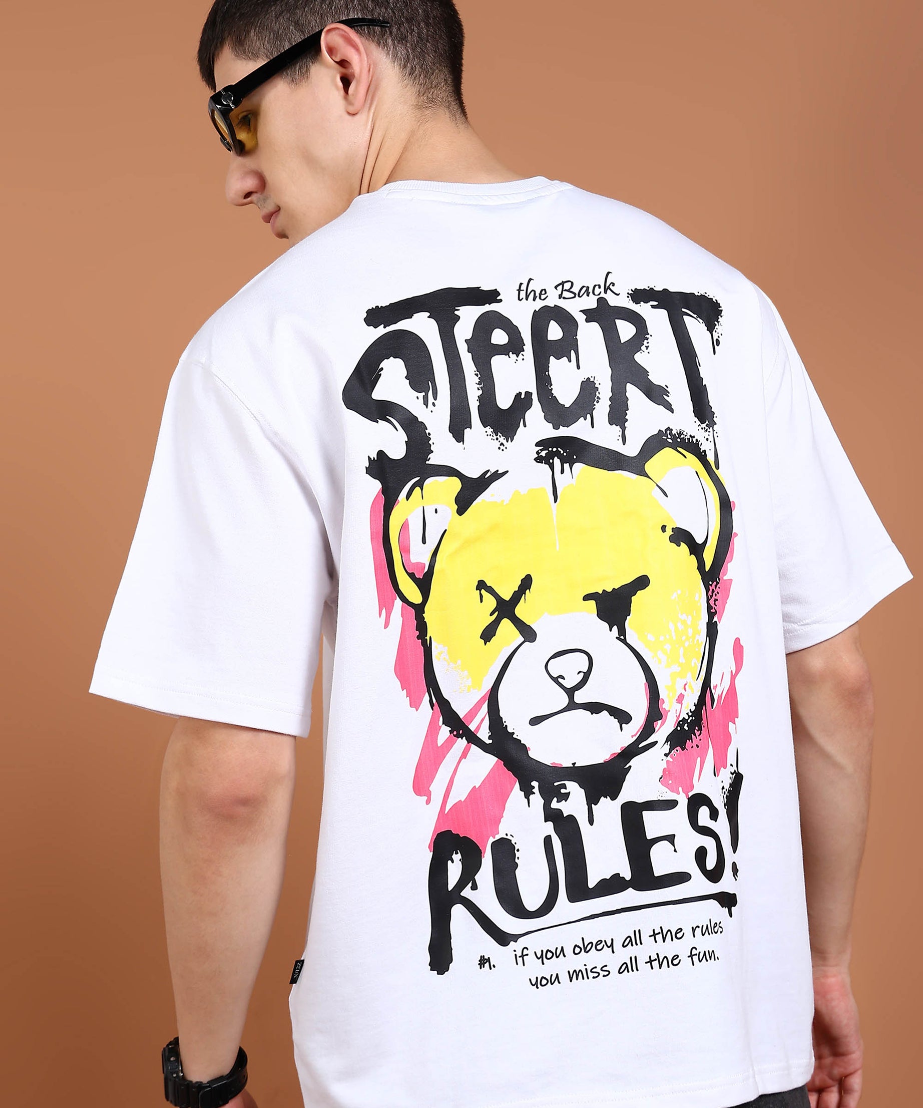 A person wearing an oversized white t-shirt with a graphic of a bear and the text 'STREET RULES' on the back.
