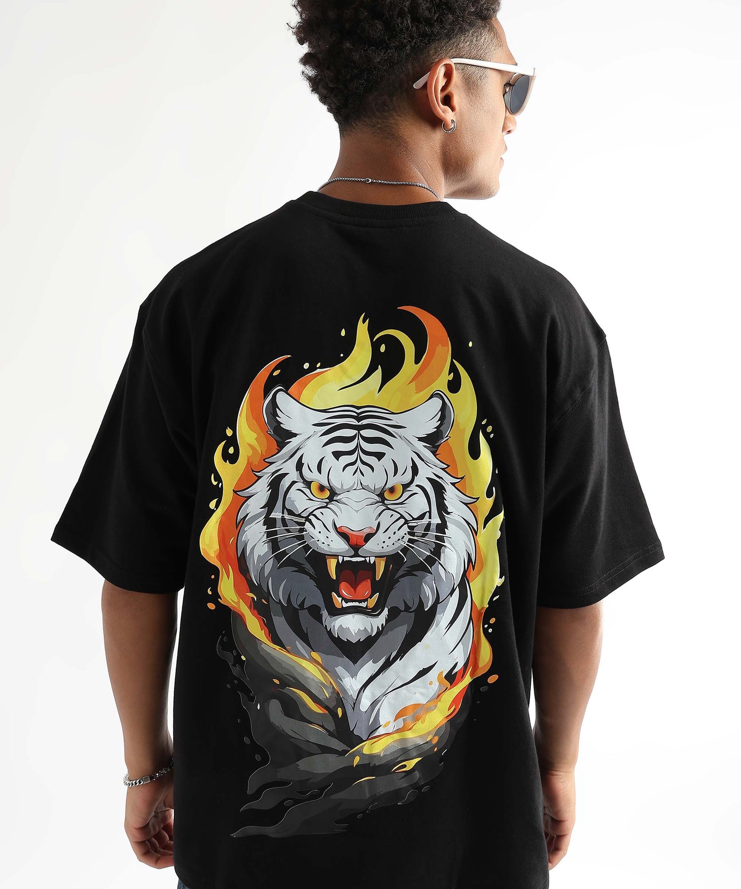 A person wearing an oversized black t-shirt with a graphic of a white tiger with flames around it.