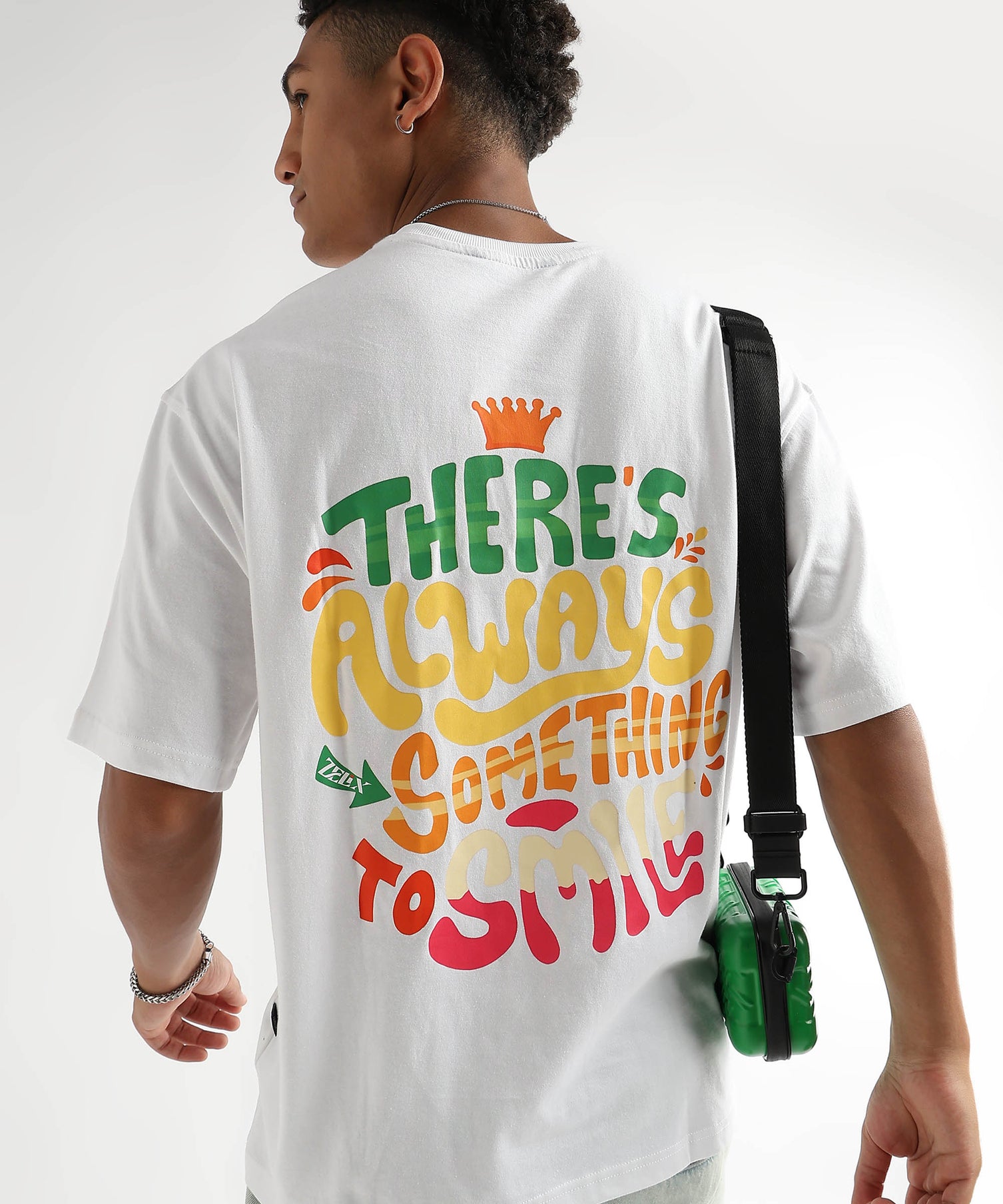 A person wearing an over-sized white T-shirt with colorful text on the back