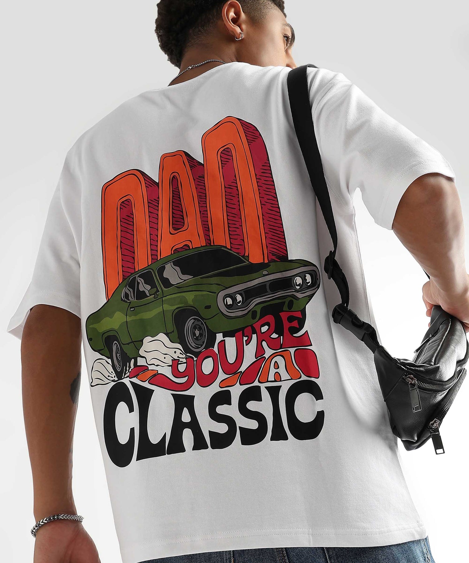 A person wearing an oversized white t-shirt with a retro-inspired graphic that includes the text 'DAD CLASSIC' and an image of a car.